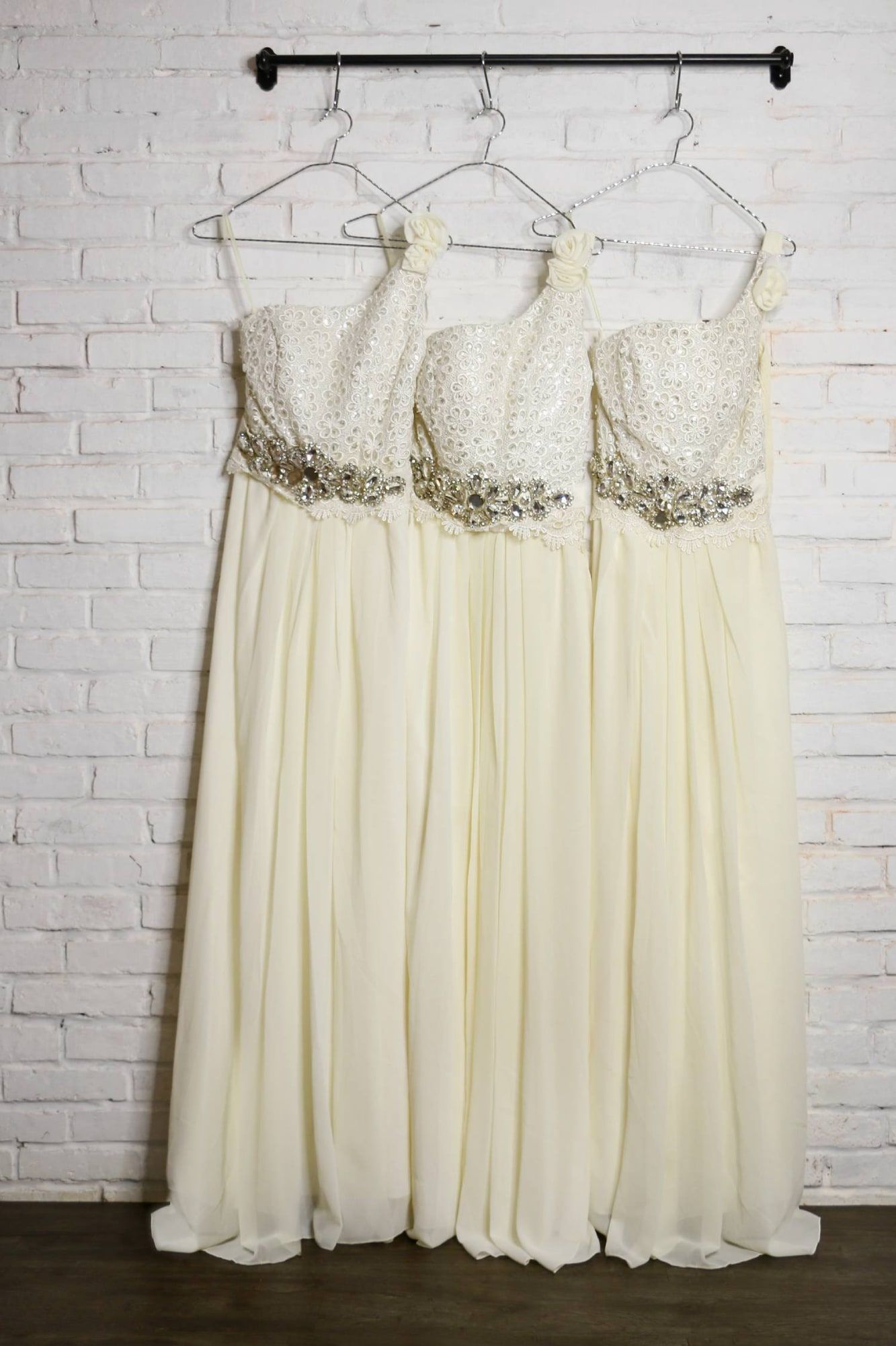 Tiga gaun bridesmaid warna krem tergantung di rak