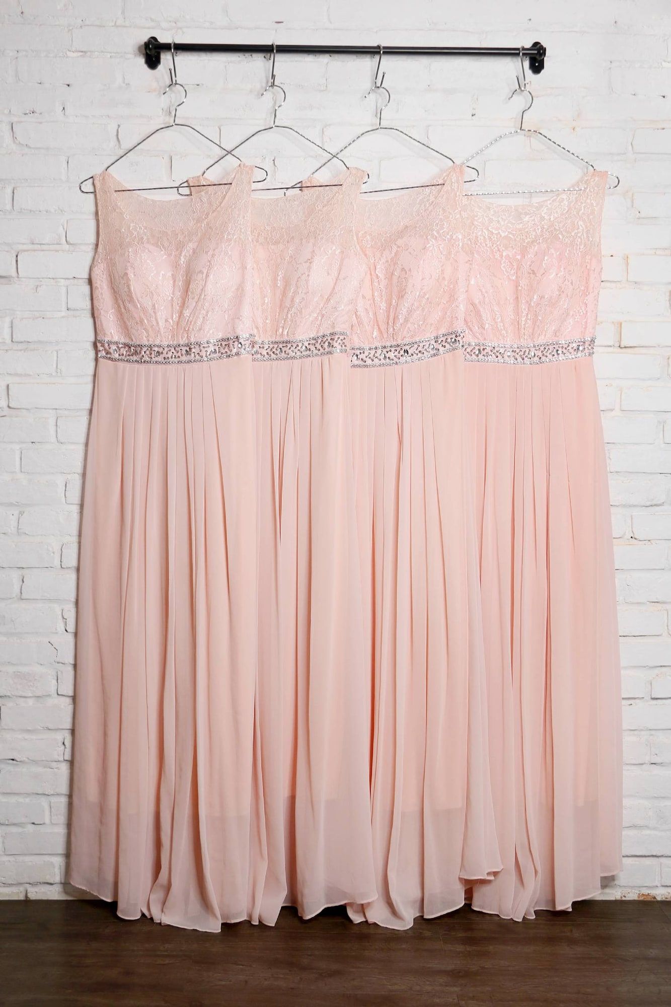 Empat gaun bridesmaid warna pink muda tergantung di rak