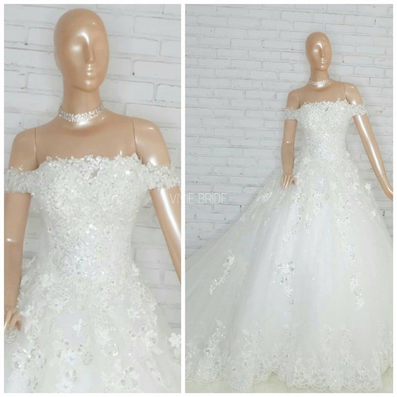 Gaun pengantin off-shoulder renda putih pada manekin, tampak detail dan utuh