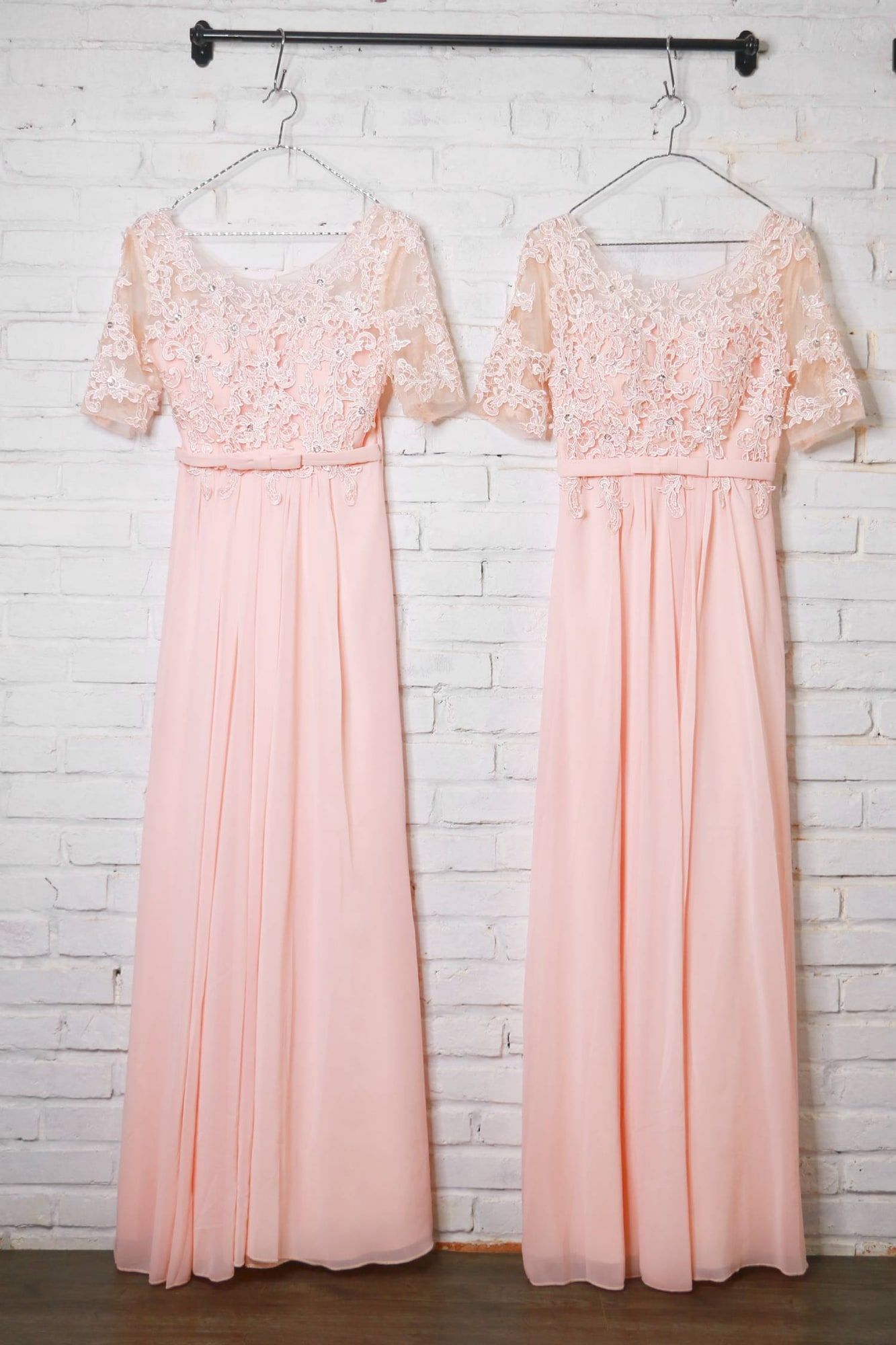 Dua gaun panjang warna peach untuk ibu pengantin tergantung di rak