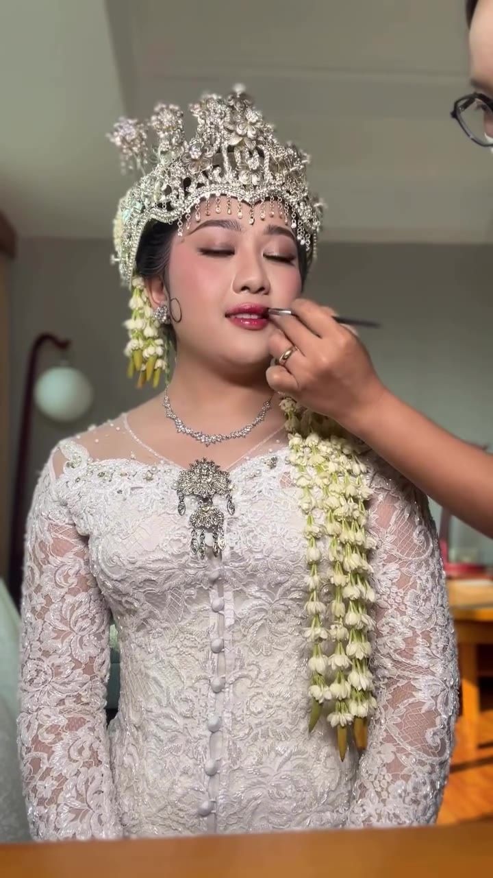 Makeup artist merias bibir pengantin wanita berkebaya putih dengan siger