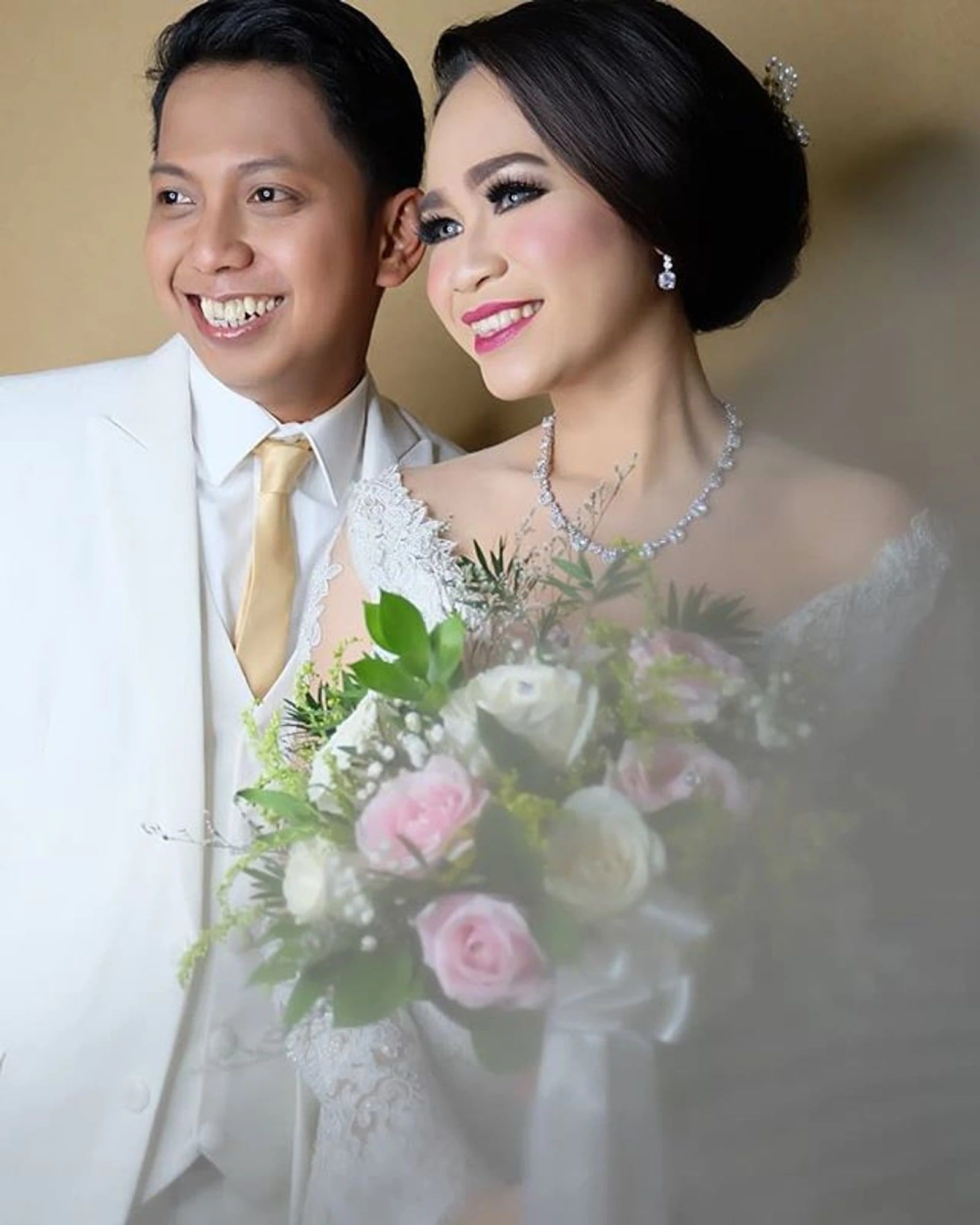 Pasangan pengantin tersenyum, pengantin wanita memegang buket bunga pastel
