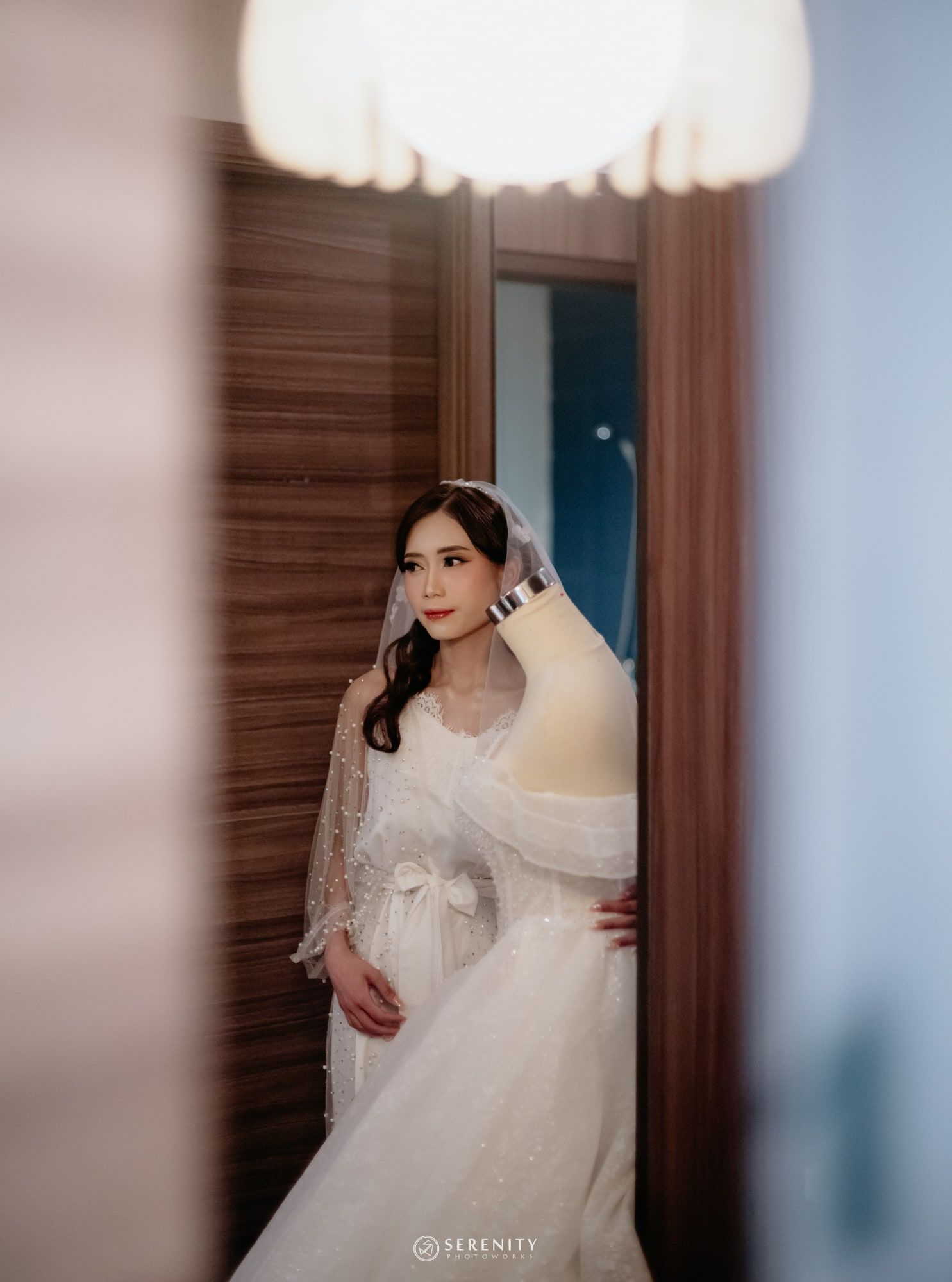 Pengantin wanita terlihat dari celah pintu, berdiri di samping gaun pengantin