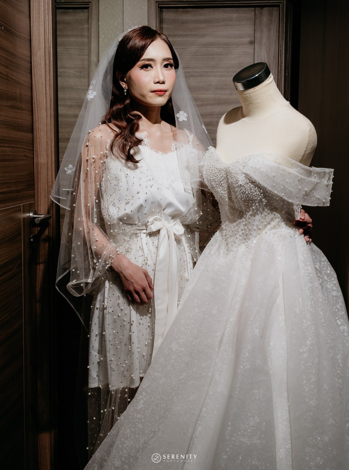 Pengantin wanita berdiri di samping gaun ball gown pada manekin